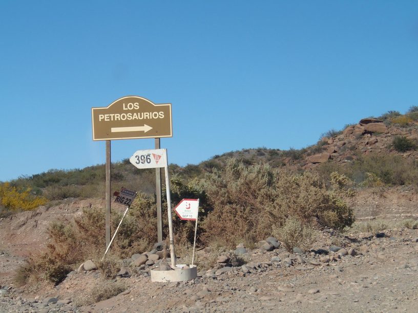 Camino de acceso en Aguada Pichana, cerca de Añelo (Neuquén), con carteles de equipos de perforación.
