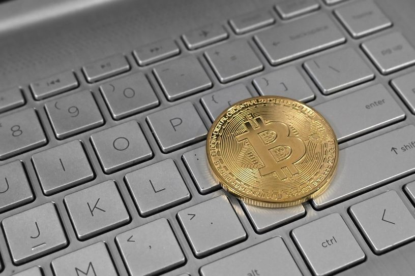 Una moneda de bitcoin sobre el teclado de una computadora portátil